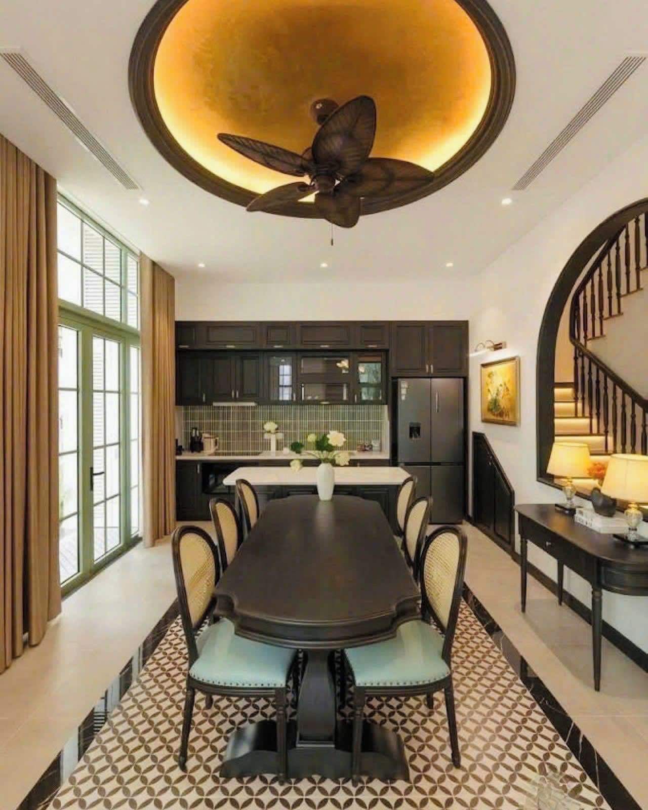 Una cocina moderna con armarios oscuros, una isla central y un comedor con una mesa grande y sillas.