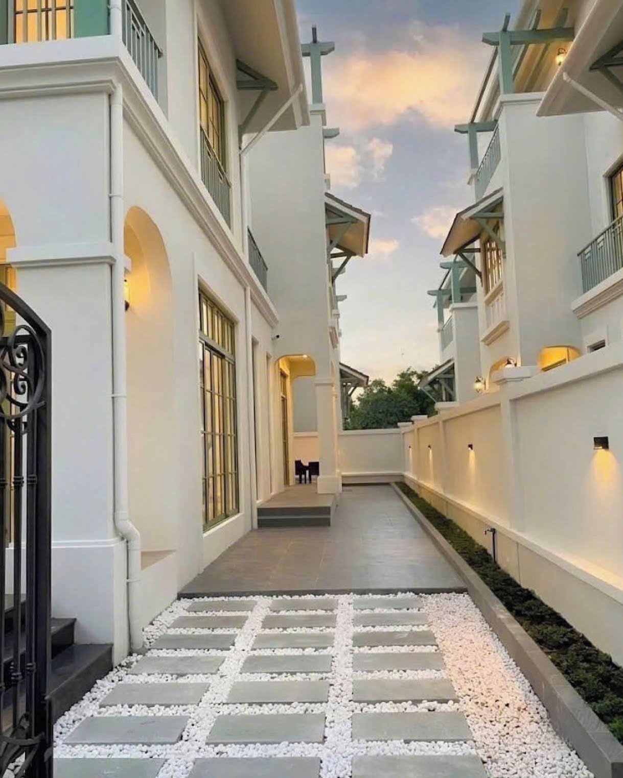 A pathway leading to a building with a gated entrance, a staircase, and a view of the sky.