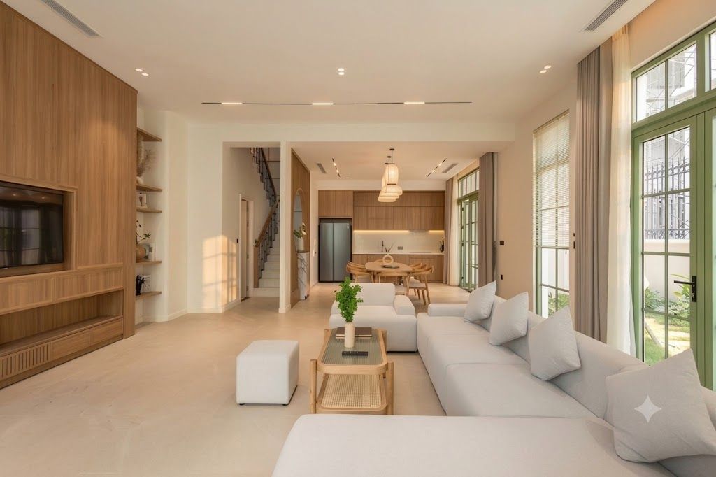 A modern living room with a sofa, a coffee table, and a TV. There is a kitchen area with a dining table and chairs.
