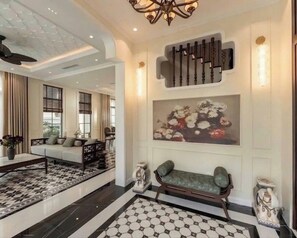 Eine geräumige Lobby mit einem gemusterten Boden, einer Sitzecke mit einer Bank, einem wandmontierten Klavier und einem großen Blumenkunstwerk.