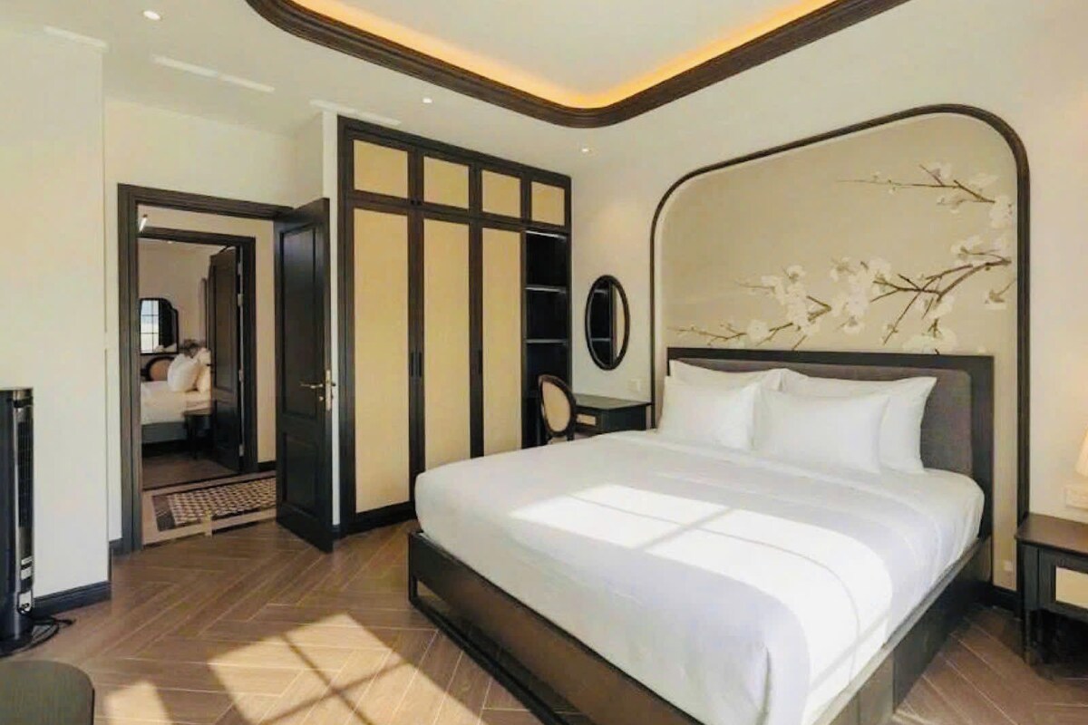 A hotel room with a large bed, a wardrobe, a desk, and a mirror.