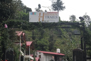 Señal que indica 'Hidden Trails', con una vista de un edificio y una puerta al fondo.
