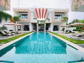 Ein modernes Hotel mit einem zentralen Schwimmbad, Loungebereichen und einer Stein-Fassade.