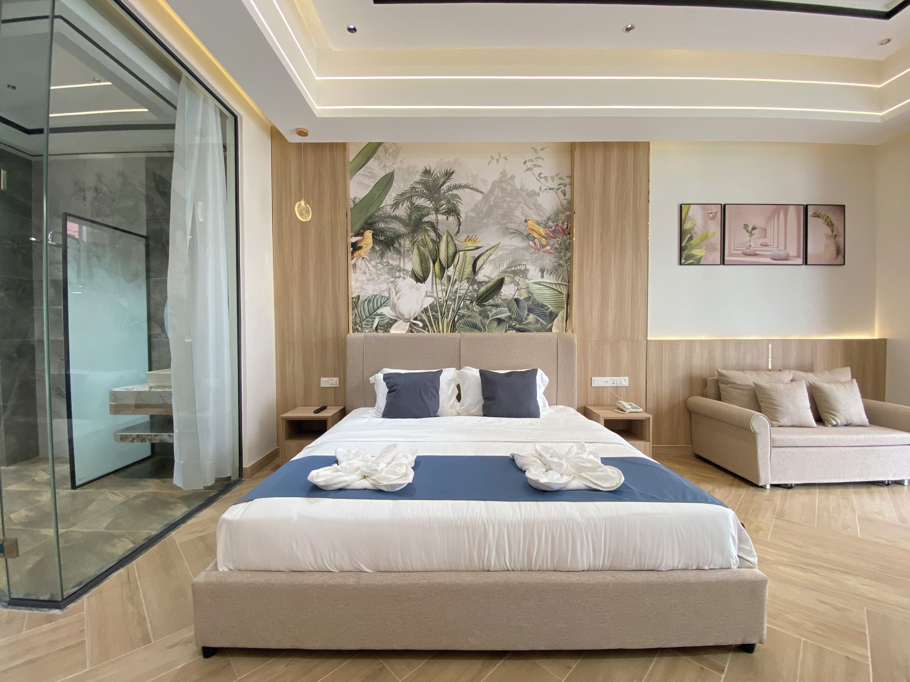 Una habitación de hotel moderna con una cama grande, un sofá y un mural en la pared.