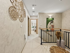 A hallway with a modern design, featuring a staircase with a black railing, a decorative wall piece, and a traditional Japanese artwork. - Spacious 3BR Villa | Villanova | Gated Community (Dubai)