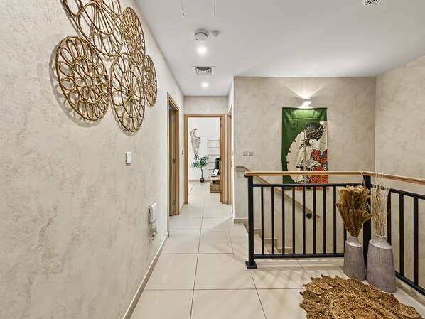 Ein Flur im modernen Design, mit einer Treppe, einem schwarzen Geländer, einer Wanddekoration und einem traditionellen japanischen Kunstwerk.