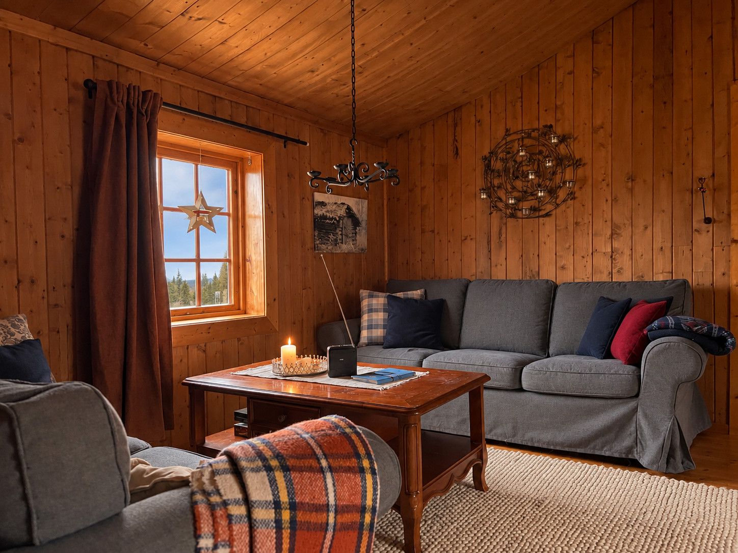 Ein gemütliches Blockhaus-Interieur mit Holzbalkendecke, einem grauen Sofa mit Kissen, einem kleinen Tisch mit Kerze und einem Fenster mit Vorhängen.