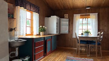 A wooden cabin interior with a kitchen area, including a sink, cabinets, and a refrigerator.