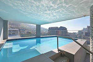 An indoor swimming pool with a city view, a glass barrier, and a tiled floor. - Cape Town City 2Bed, Views, Balcony, Pool (Cape Town)