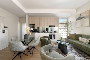 A modern living room with a dining area, a kitchen with wooden cabinets, and a view of the city. - Cape Town City 2-Bed, Views, Balcony & Pool (Cape Town)
