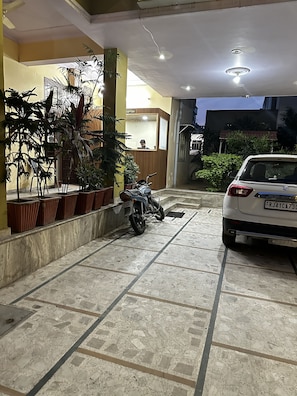 Uma área de recepção com balcão, plantas em vasos e uma motocicleta estacionada em primeiro plano.