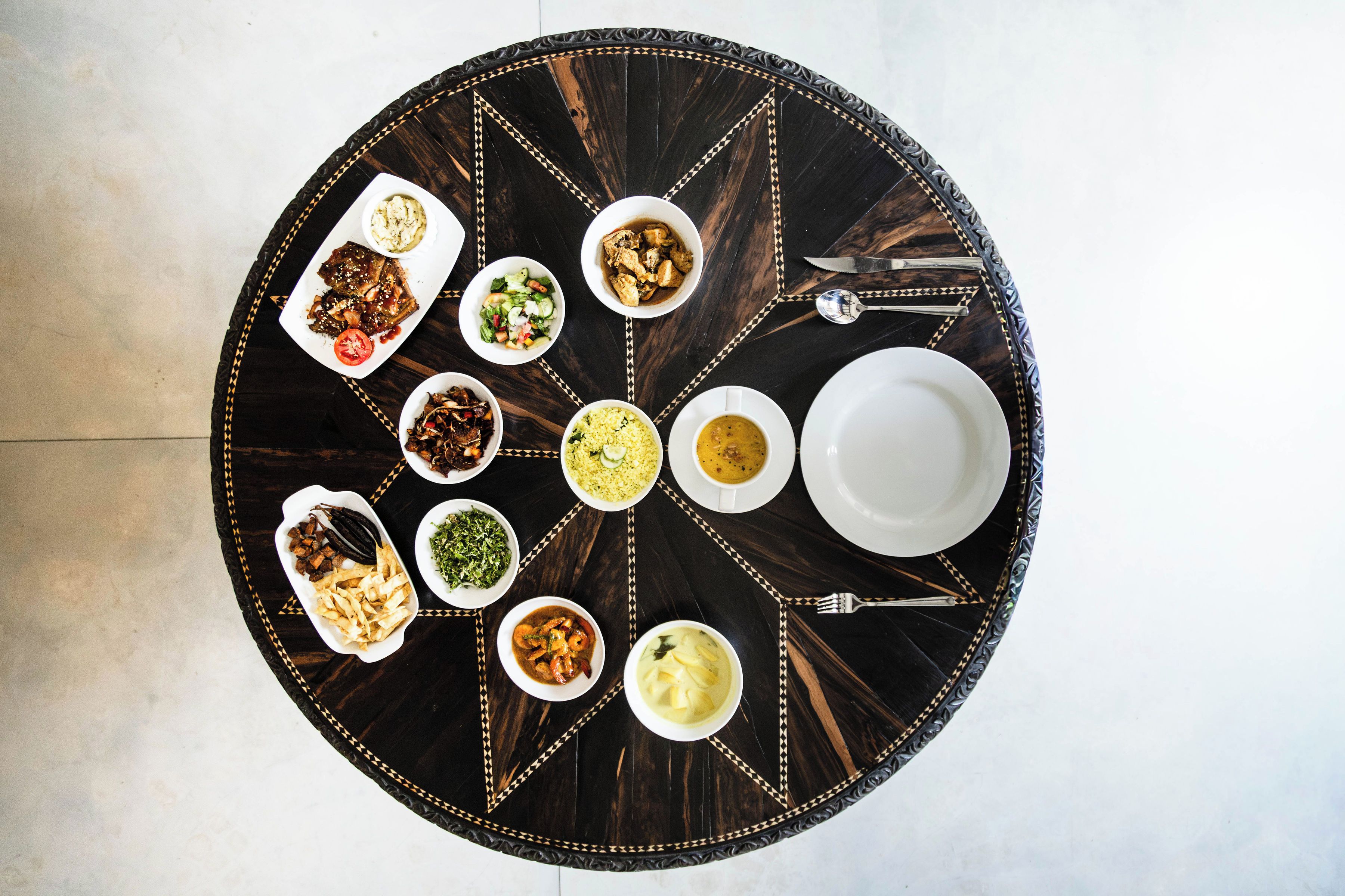 Una mesa redonda para comer con diferentes platos y cubiertos.