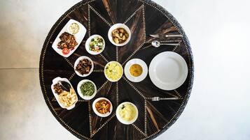 Una mesa redonda para comer con diferentes platos y cubiertos.