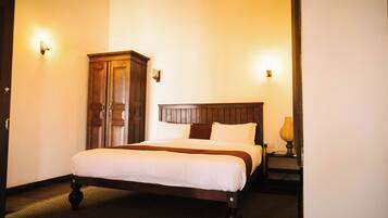 A hotel room with a wooden bed, a wardrobe, and two wall-mounted lamps.