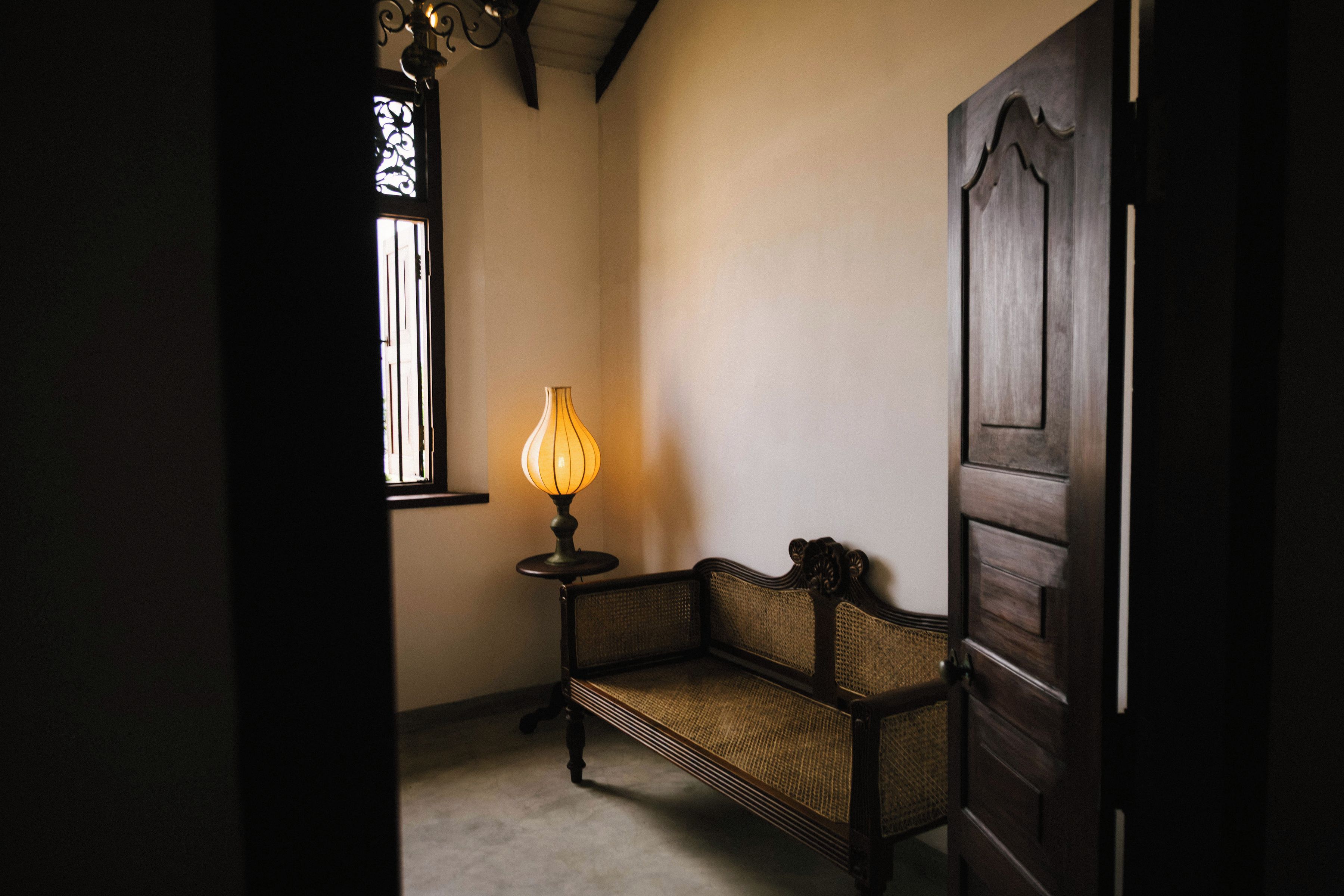 A hallway with a bench, a lamp, and a door.