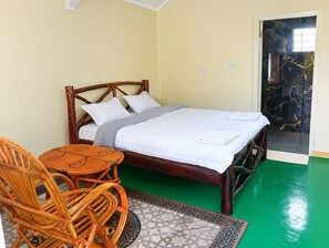 Una habitación con cama, una silla y una mesita.