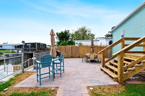 Un espace patio aménagé avec du mobilier d’extérieur, un escalier en bois et une clôture.