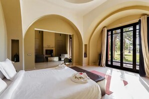 A hotel room with a large bed, a sitting area with a TV, and a view of the outdoors.