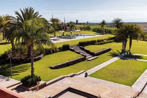 A landscaped garden with a swimming pool, palm trees, and a clear sky. - Atlas-view estate with staff, 20m pool and tennis (Marrakesh)