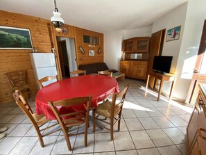 A dining area with a round table covered in a red tablecloth, surrounded by wooden chairs. - 250 meters from the ski lifts, 2nd floor, parking, TV, ski locker, 55 m², Arêches-Beaufort (Beaufort)
