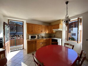 A kitchen with wooden cabinets, a microwave, a sink, and a dining table with chairs. - 250 meters from the ski lifts, 2nd floor, parking, TV, ski locker, 55 m², Arêches-Beaufort (Beaufort)