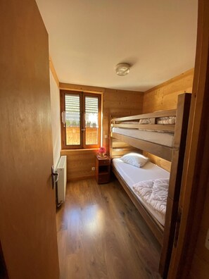 A compact room with a bunk bed, a small bedside table with a lamp, and a window with blinds. - 250 meters from the ski lifts, 2nd floor, parking, TV, ski locker, 55 m², Arêches-Beaufort (Beaufort)