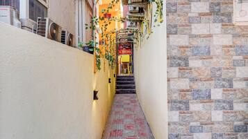 Un estrecho callejón con suelo de baldosas, una escalera y un edificio de fachada de piedra.