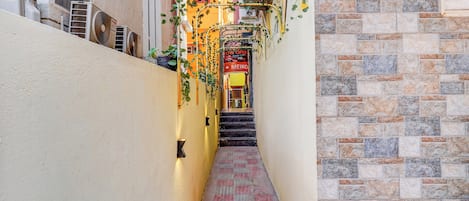 A narrow alleyway with a tiled floor, a staircase, and a building with a stone facade.