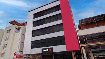 Un hotel con fachada moderna, que presenta una llamativa banda vertical roja y un cartel del Hotel OYO Paradise Inn.