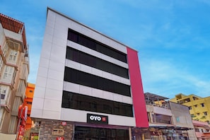 Un edificio de hotel con fachada moderna, múltiples ventanas y un llamativo acento rojo vertical.