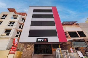 A hotel building with a prominent red vertical stripe, a sign reading 'OYO Hotel Paradise Inn', and a visible entrance with steps leading up to the door. - Hotel O Paradise Inn (Bangalore)