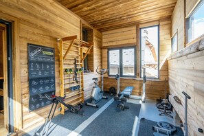 A gym with wooden walls, exercise equipment, and a chalkboard with workout instructions. - Chalet, fitness, terrace, fireplace or stove, parking, tv, ski locker, 310m², Les 2 Alpes (Mont-de-Lans)