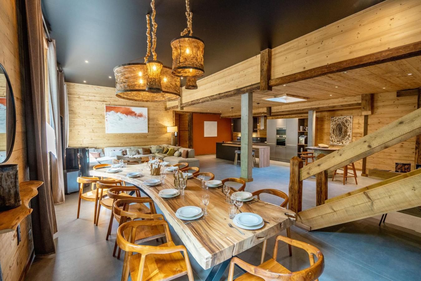 Un vaste espace dédié à la salle à manger, avec une longue table en bois dressée pour le repas, entourée de chaises en bois.