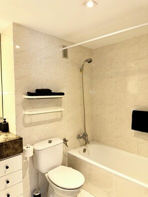 Ein Badezimmer mit Toilette, einer Badewanne, einer Dusche und einem Handtuchhalter.