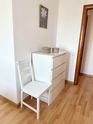 A white chair and a white dresser with two woven baskets on top. - 3-Bedroom Apartment by the Sea (Vilassar de Mar)