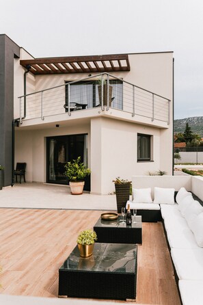 A modern two-story building with a balcony, outdoor seating area, and potted plants. - Villa B4 in Ibenik (Sibenik)