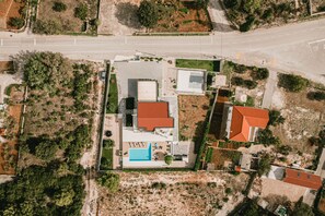 An aerial view of a property with a swimming pool, a red-roofed building, and a paved area with a white fence. - Villa B4 in Ibenik (Sibenik)