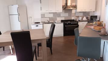 Une cuisine moderne avec des meubles blancs, une cuisinière noire et un coin repas comprenant une table en bois et des chaises noires.