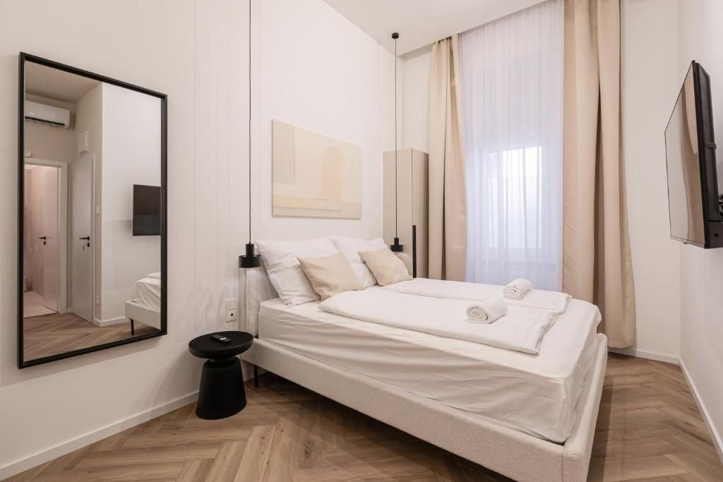 A modern bedroom with a bed, a mirror, a bedside table, and a TV.