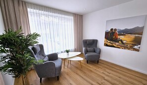 A room with two grey armchairs, a small white table, a large potted plant, and a painting of a mountainous landscape. - Deluxe Apartment in the Stubai Valley—where high standards meet cozy comfort (Fulpmes)