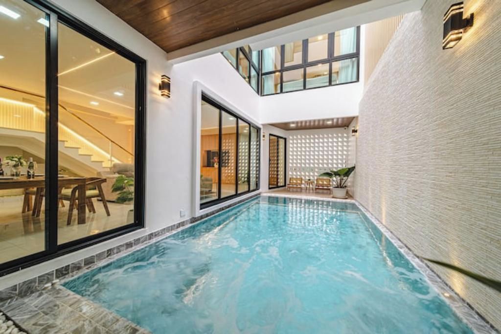 En indendørs swimmingpool med udsigt til en trappe og et spiseområde.
