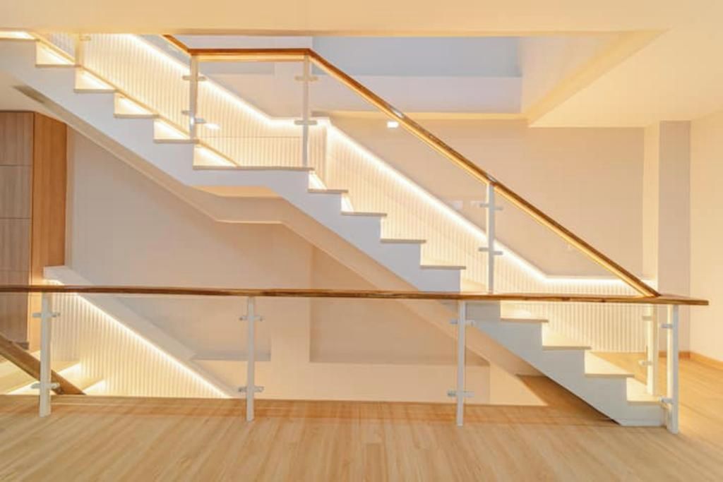 A modern interior with a staircase, wooden flooring, and a glass railing.
