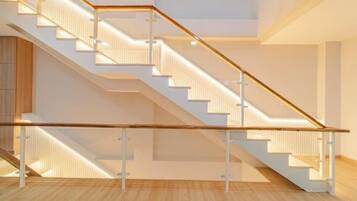A modern interior with a staircase, wooden flooring, and a glass railing.