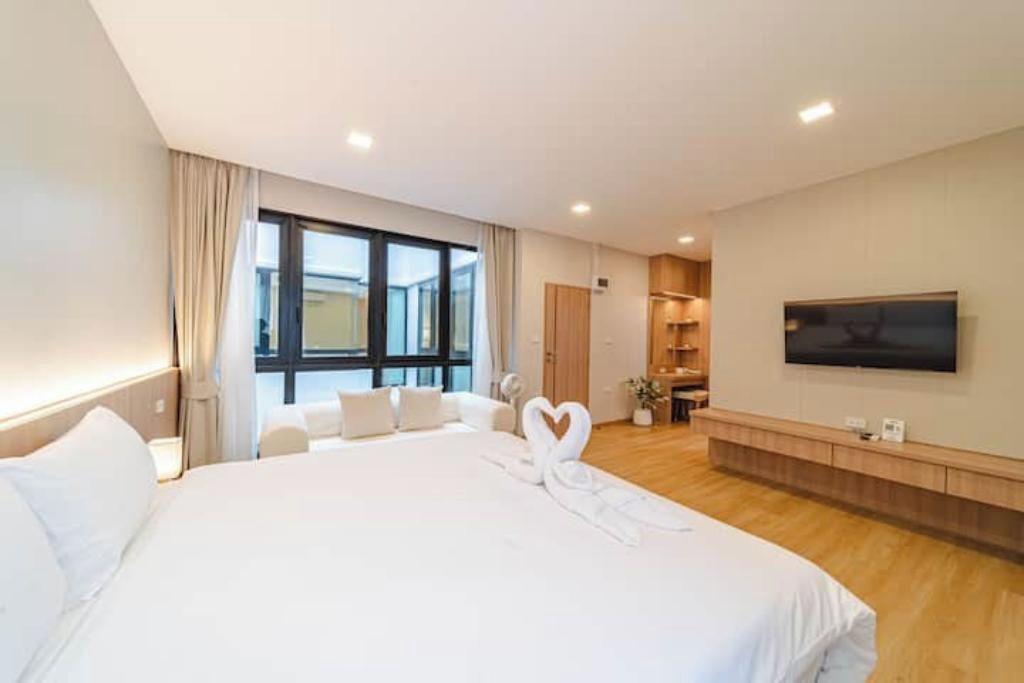 A hotel room with a large bed, a TV mounted on the wall, and a view of the city through the window.