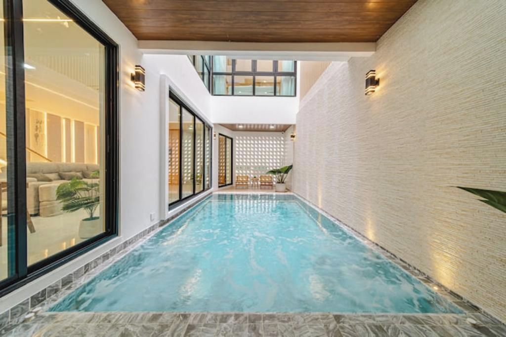 A swimming pool with a tiled floor, surrounded by walls and a ceiling with wooden panels.