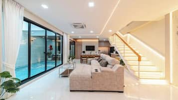 Un salon moderne avec un grand canapé, un coin repas et un escalier.