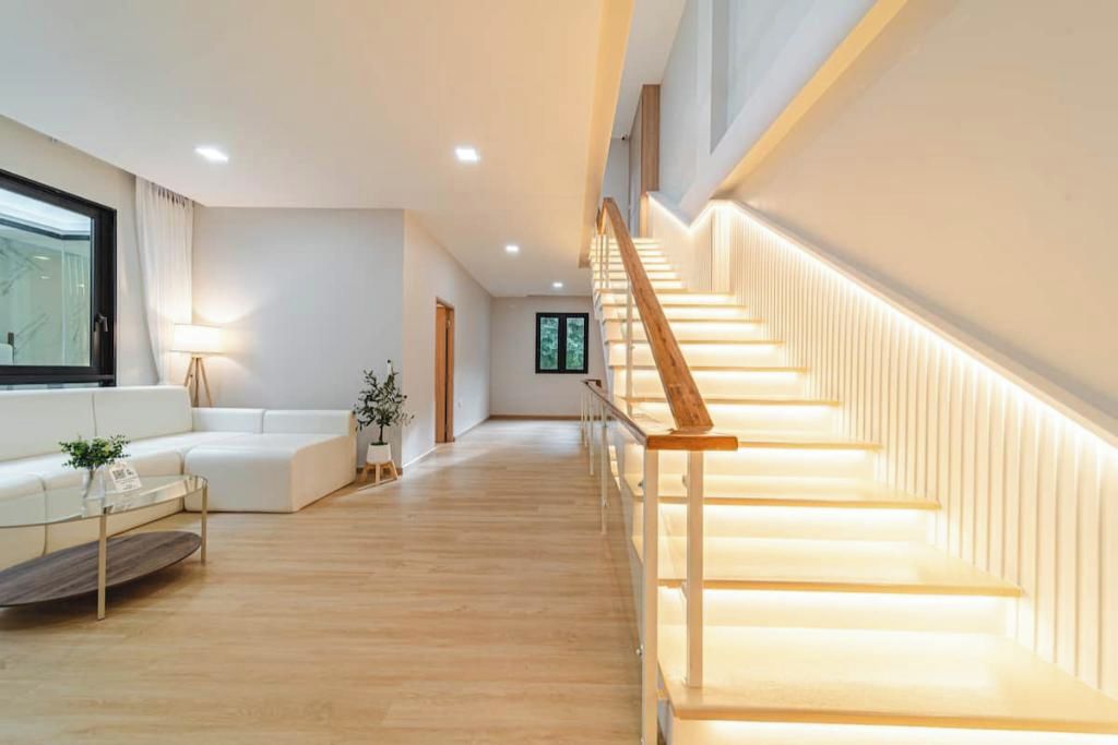 Un vaste espace de vie comprenant un escalier en bois, un canapé, une table basse et une lampe.