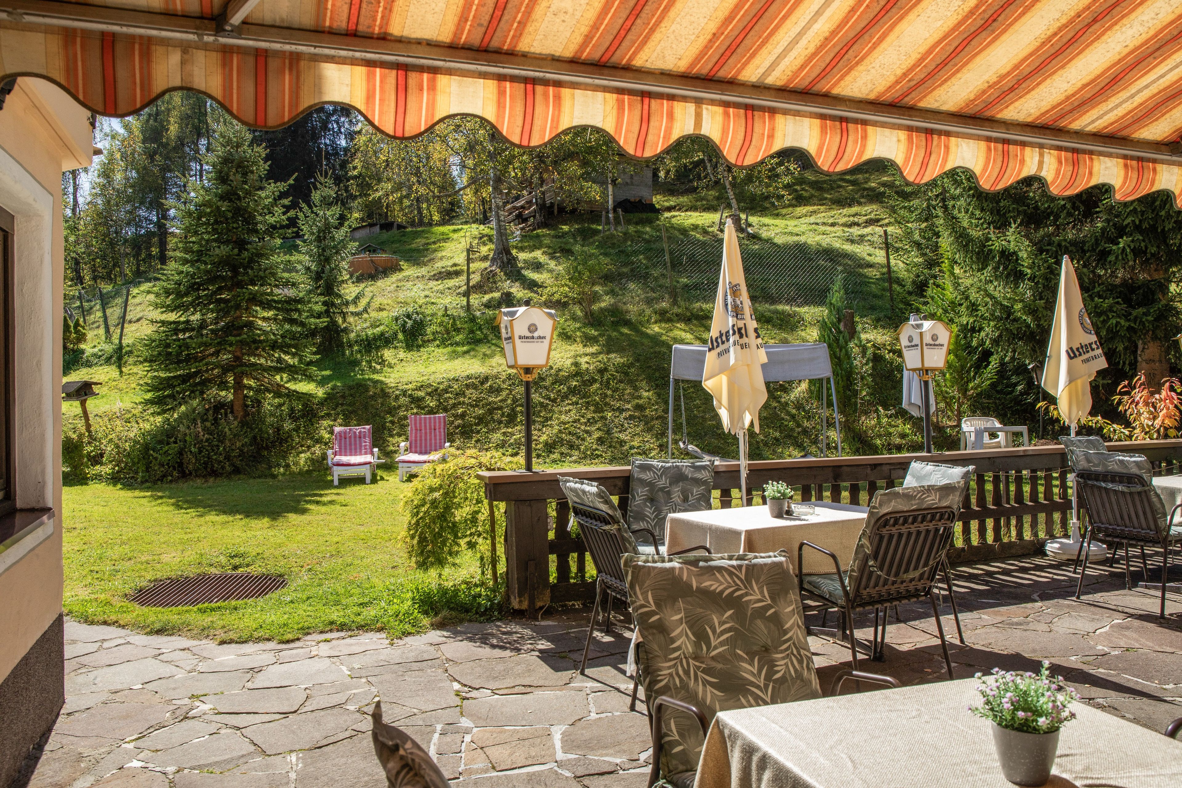 An outdoor patio with stone flooring, tables, chairs, and umbrellas.