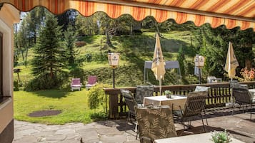 An outdoor patio with stone flooring, tables, chairs, and umbrellas.