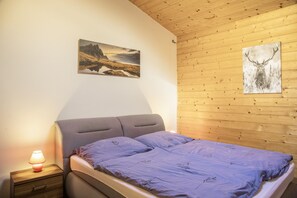 Ein Schlafzimmer mit einem Bett, einem Nachttisch, einer Lampe und zwei Bildern an der Wand.